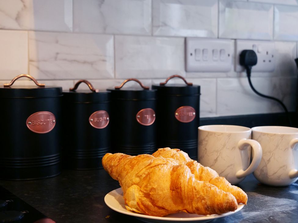 A kitchen with storage canisters and a croissant on a plate at Ashville Grange in Scarborough