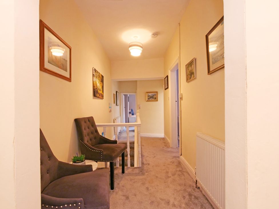 A hallway with chairs and paintings at Ashville Grange in Scarborough