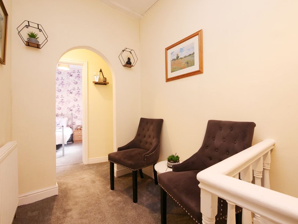A hallway with chairs and a decorative shelf at Ashville Grange in Scarborough