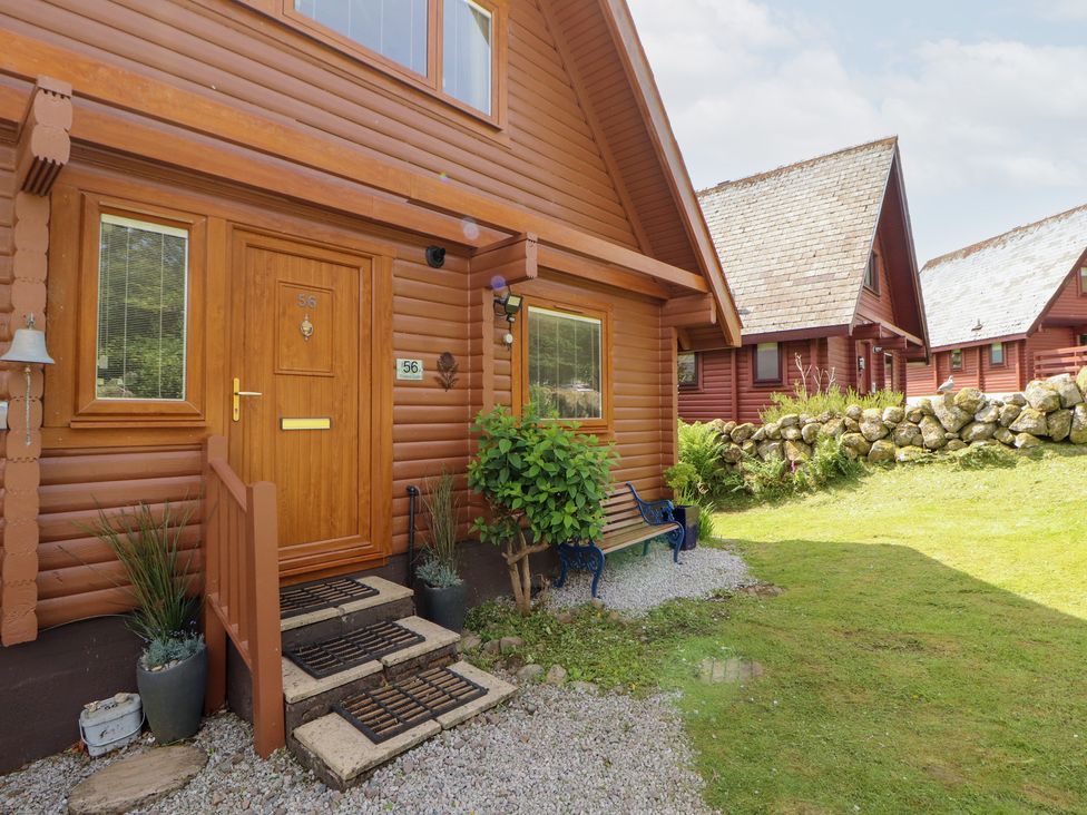 An exterior view of a wooden lodge with a front door at Thistle Dubh ('Doo') Sandyhills