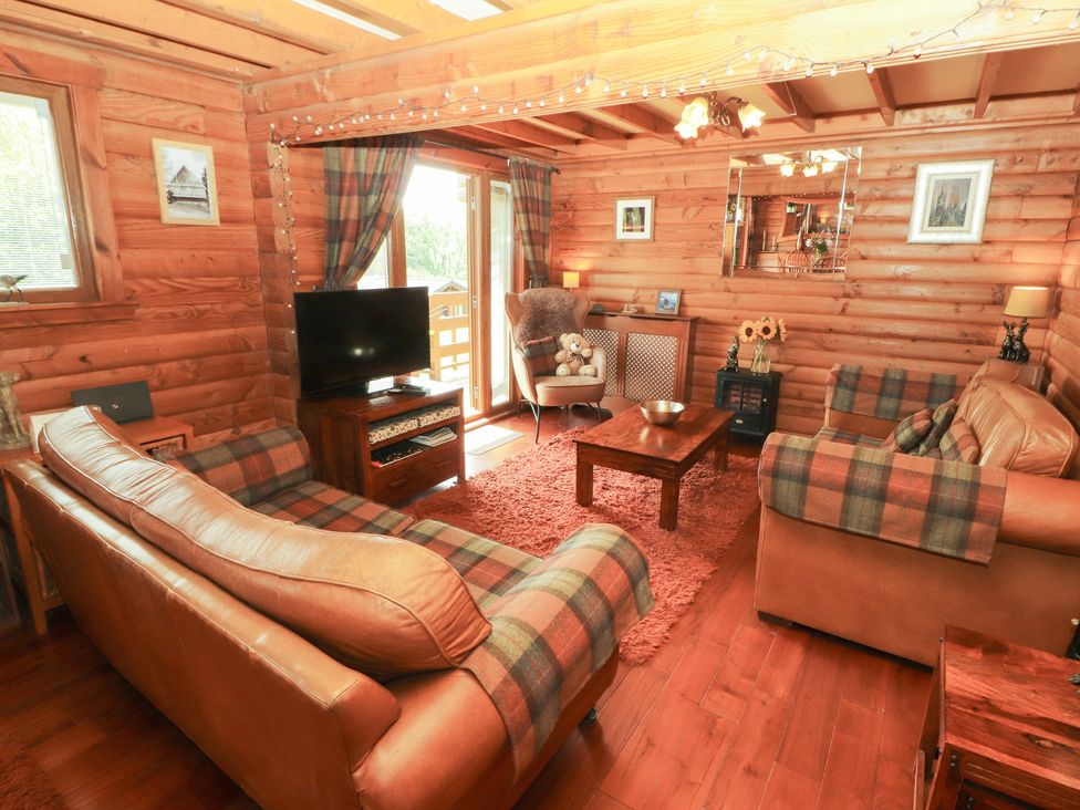 A living room with a sofa and television at Thistle Dubh ('Doo') Sandyhills