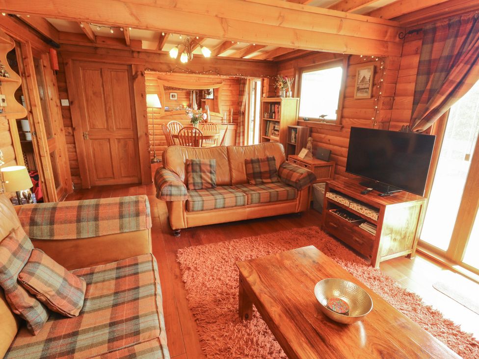 A living room with a sofa and television at Thistle Dubh ('Doo') in Sandyhills