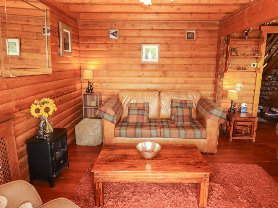 A living room with a leather sofa and wooden coffee table at Thistle Dubh ('Doo') Sandyhills