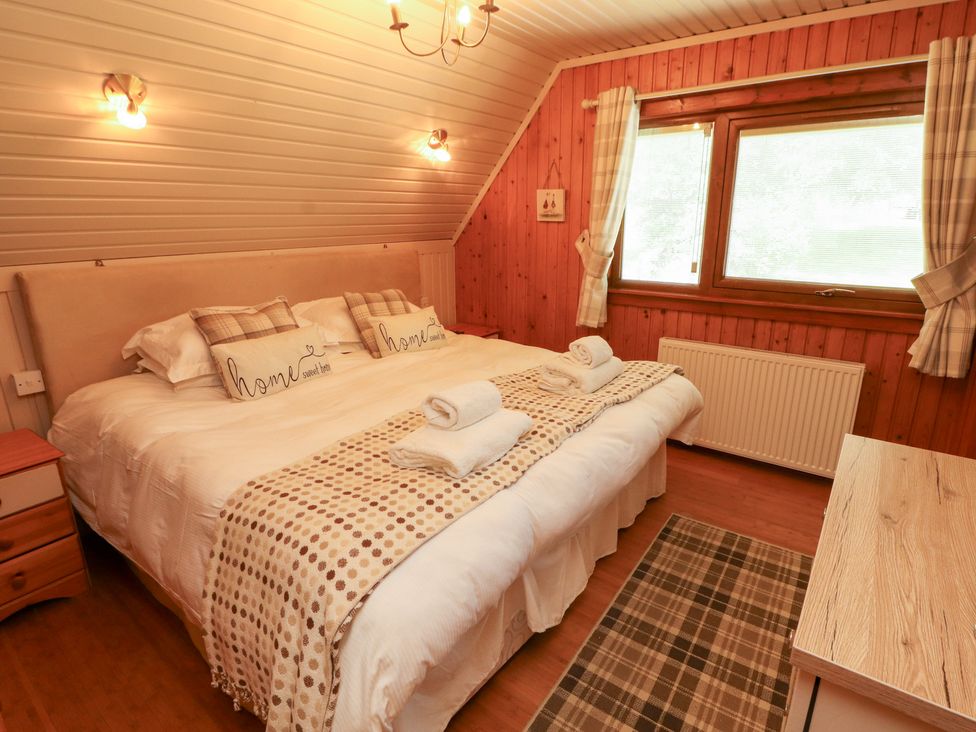 A bedroom with a bed and bedside table at Thistle Dubh ('Doo') in Sandyhills