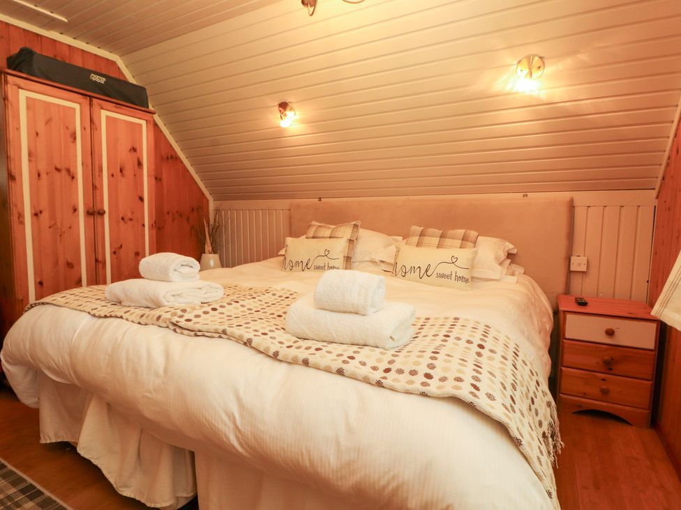 A bedroom with a bed and wardrobe at Thistle Dubh ('Doo') in Sandyhills