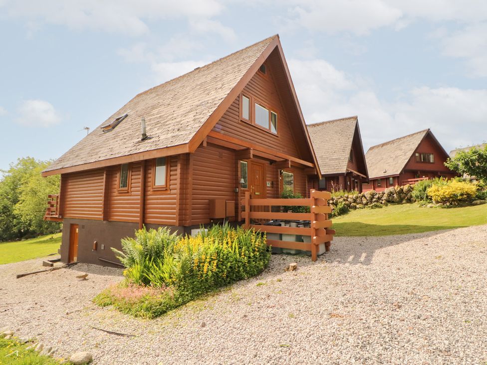 A house with a wooden exterior surrounded by garden at Thistle Dubh ('Doo') Sandyhills