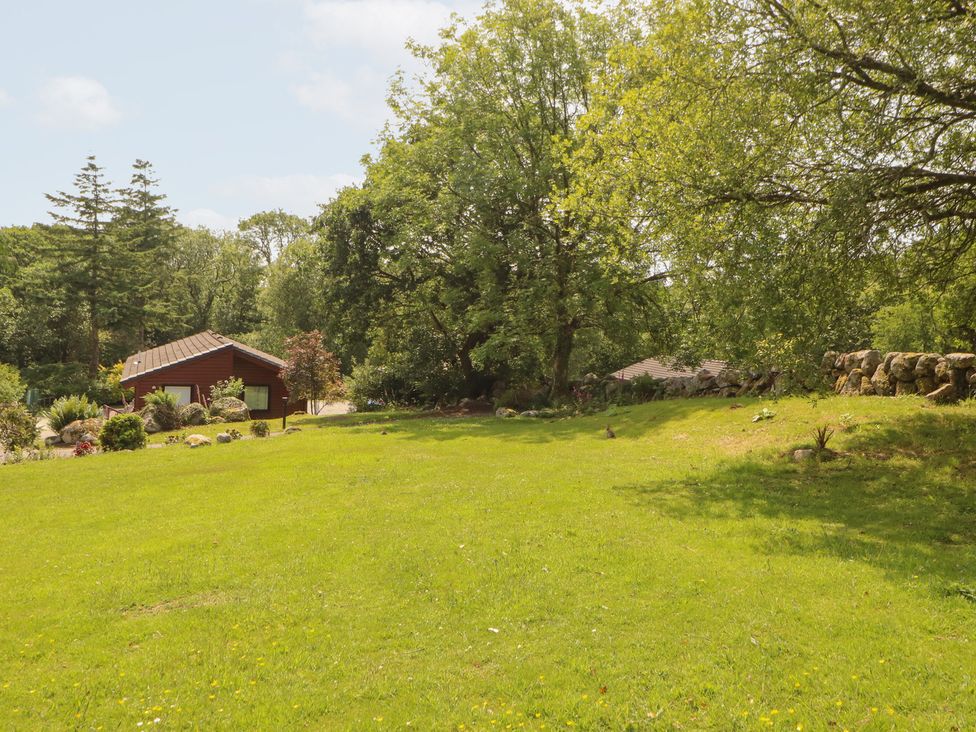 A garden with a house and trees at Thistle Dubh (