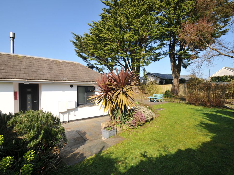 A garden with a house, plants, and seating at 6 Trelawney Court in Rock