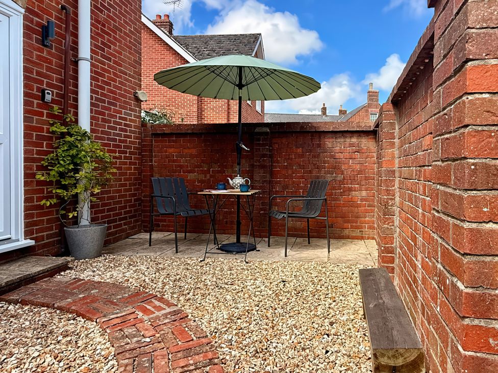 A garden with a table and chairs under an umbrella at 8 Biddlecombe Orchard Bridport