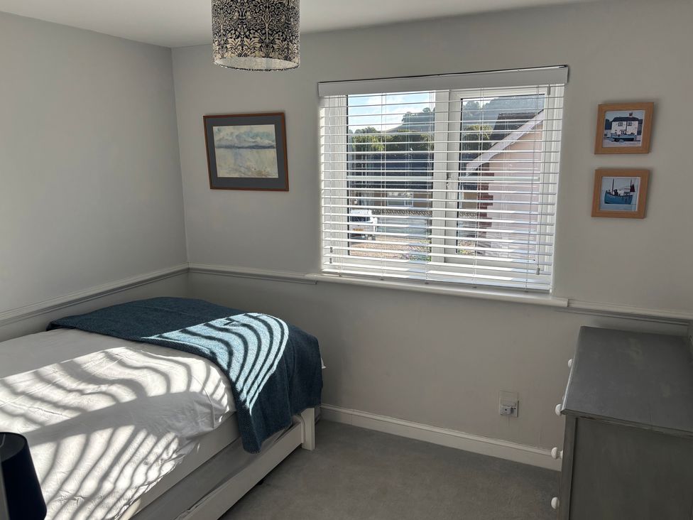 A bedroom with a bed and window at 8 Biddlecombe Orchard Bridport