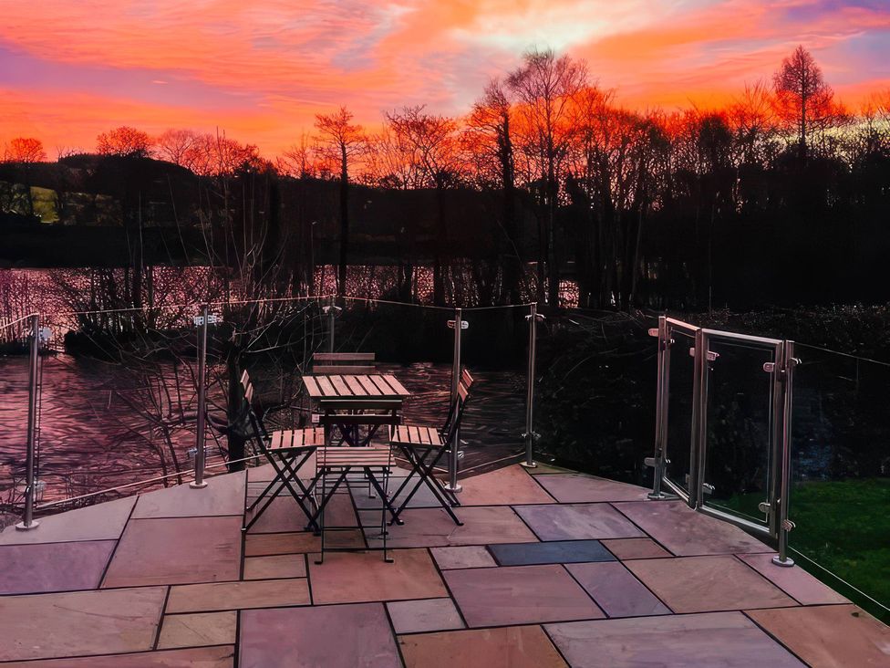 A patio with a table and chairs overlooking water at Bridge End Cottage Wark