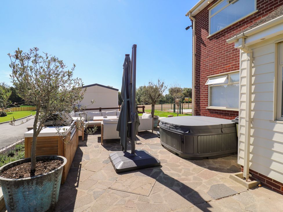 An outdoor space with a hot tub and seating area at The Farmhouse in St. Osyth