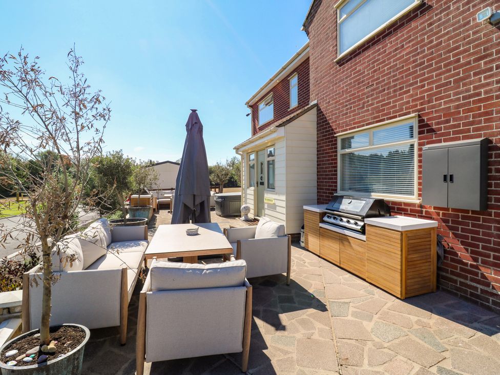 An outdoor patio with a table, chairs, and a grill at The Farmhouse in St. Osyth