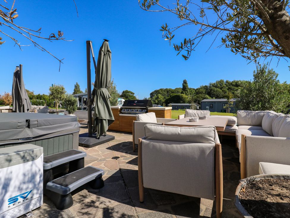 An outdoor seating area with hot tub and barbecue at The Farmhouse in St. Osyth