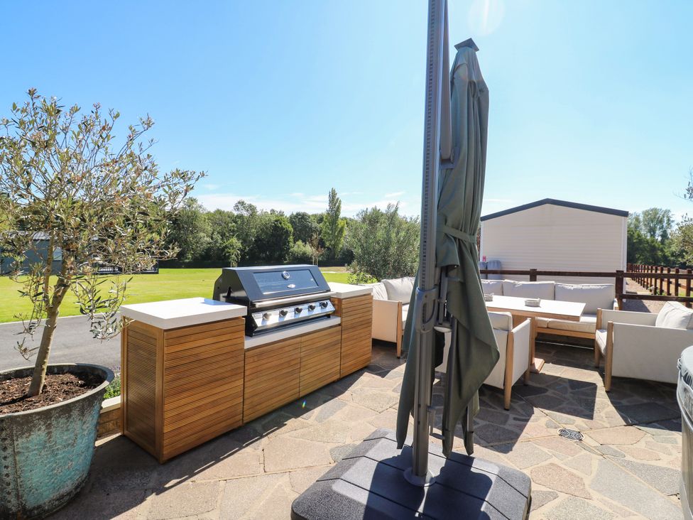An outdoor area with a grill and seating at The Farmhouse in St. Osyth