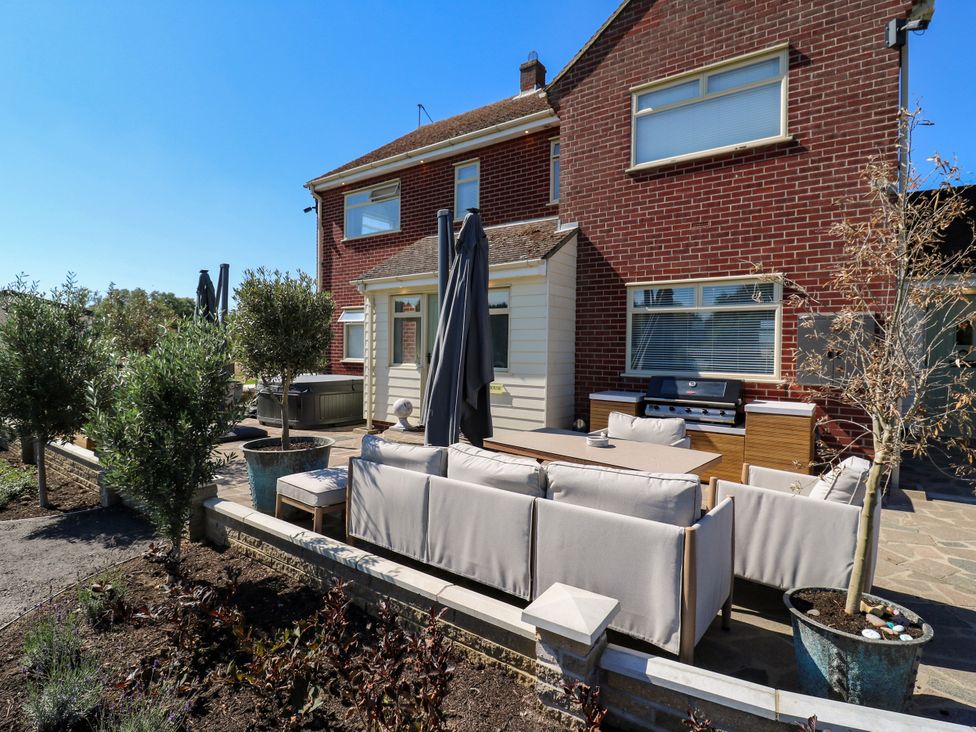 An outdoor patio with seating and grill at The Farmhouse in St. Osyth