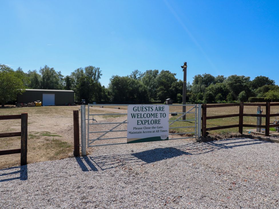 A gate leading to an open space with a sign at The Farmhouse in St. Osyth