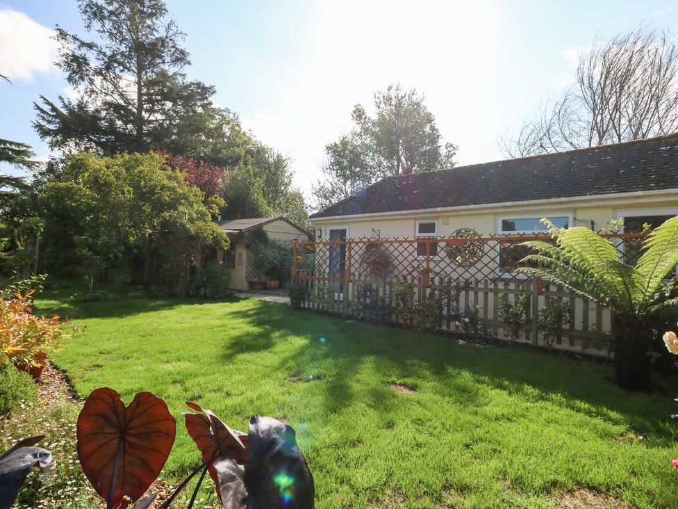 A garden with grass, fence, and shed at Little Timbers in Ringwood