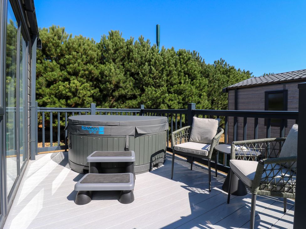 An outdoor terrace with a hot tub and seating at Lakewood Plot 2 St. Osyth