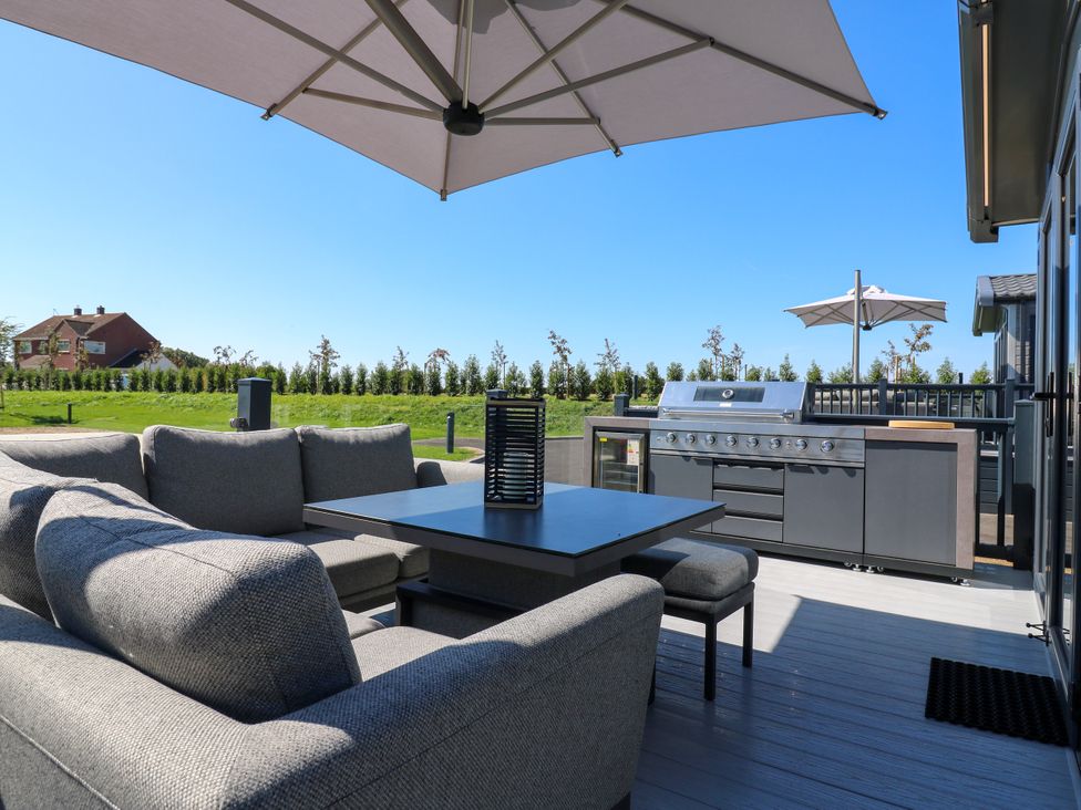 An outdoor seating area with a barbecue grill and umbrella at Lakewood Plot 2 St. Osyth