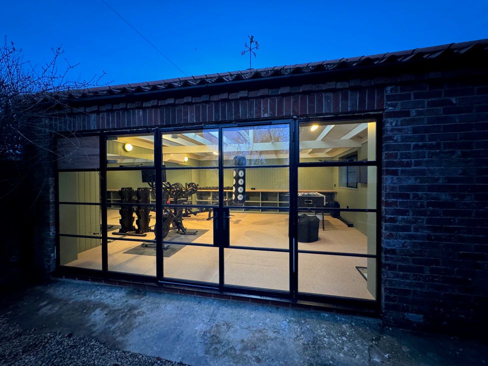 A gym with exercise equipment and weights at Oak Cottage in Somerleyton