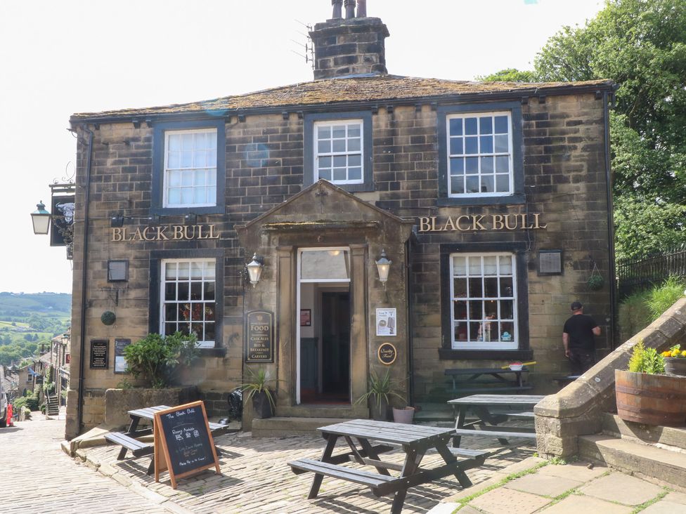 A pub facade with benches and a sign at Penny Cottage in Haworth