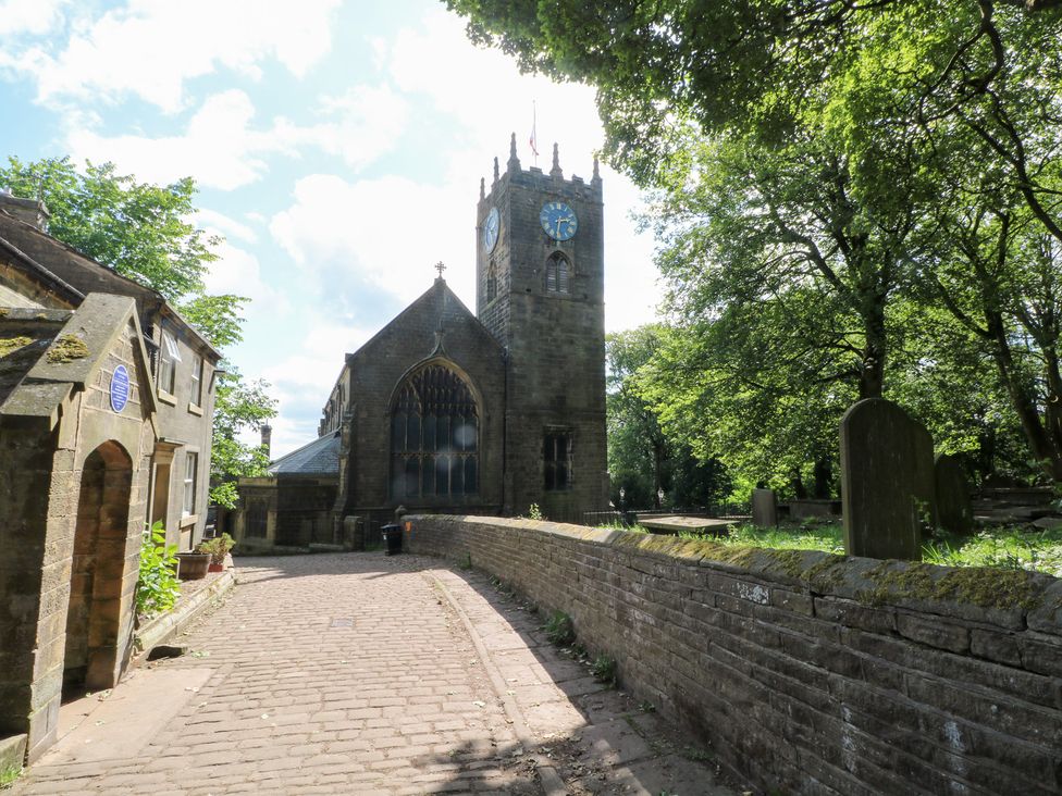 A church with a clock tower and trees in the background at Penny Cottage in Haworth