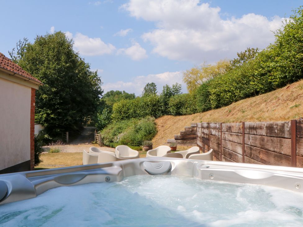 An outdoor area with a hot tub and chairs at Apple Mill Venn Ottery near Sidmouth