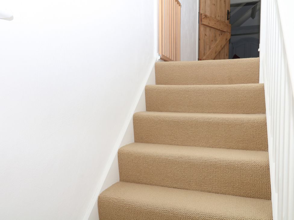 A staircase with carpet and wooden door at Apple Mill in Venn Ottery near Sidmouth
