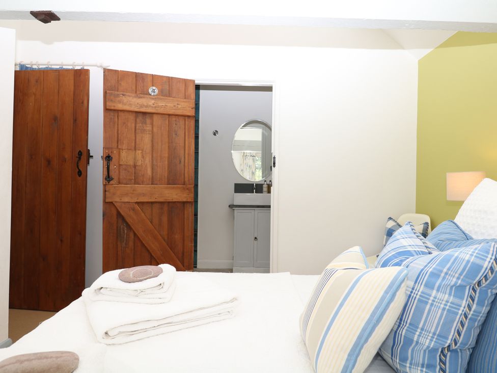 A bedroom with a bed and wooden doors at Apple Mill Venn Ottery near Sidmouth