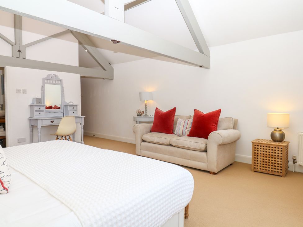 A bedroom with a bed, sofa and vanity at Apple Mill in Venn Ottery near Sidmouth