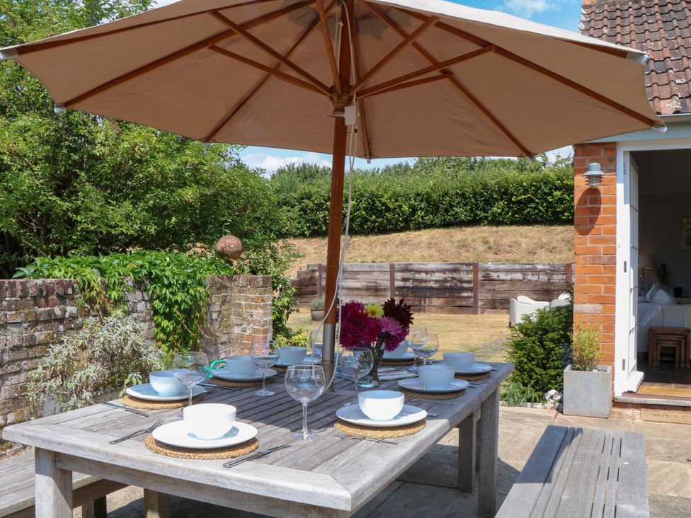 An outdoor dining area with table and umbrella at Apple Mill in Venn Ottery near Sidmouth