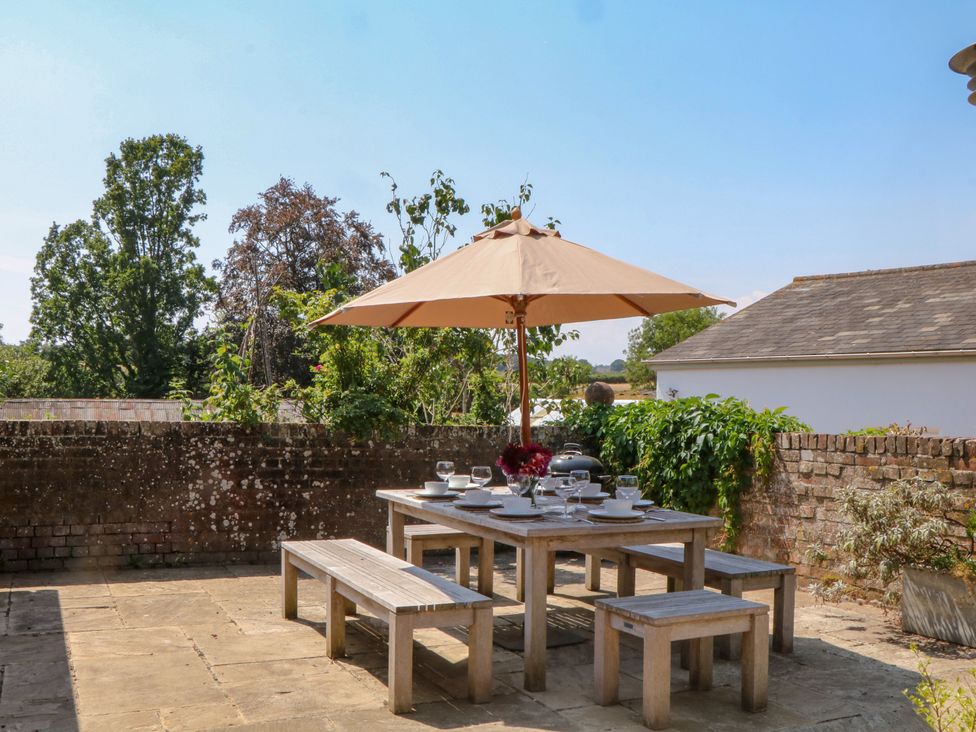 An outdoor dining area with a table and umbrella at Apple Mill in Venn Ottery near Sidmouth