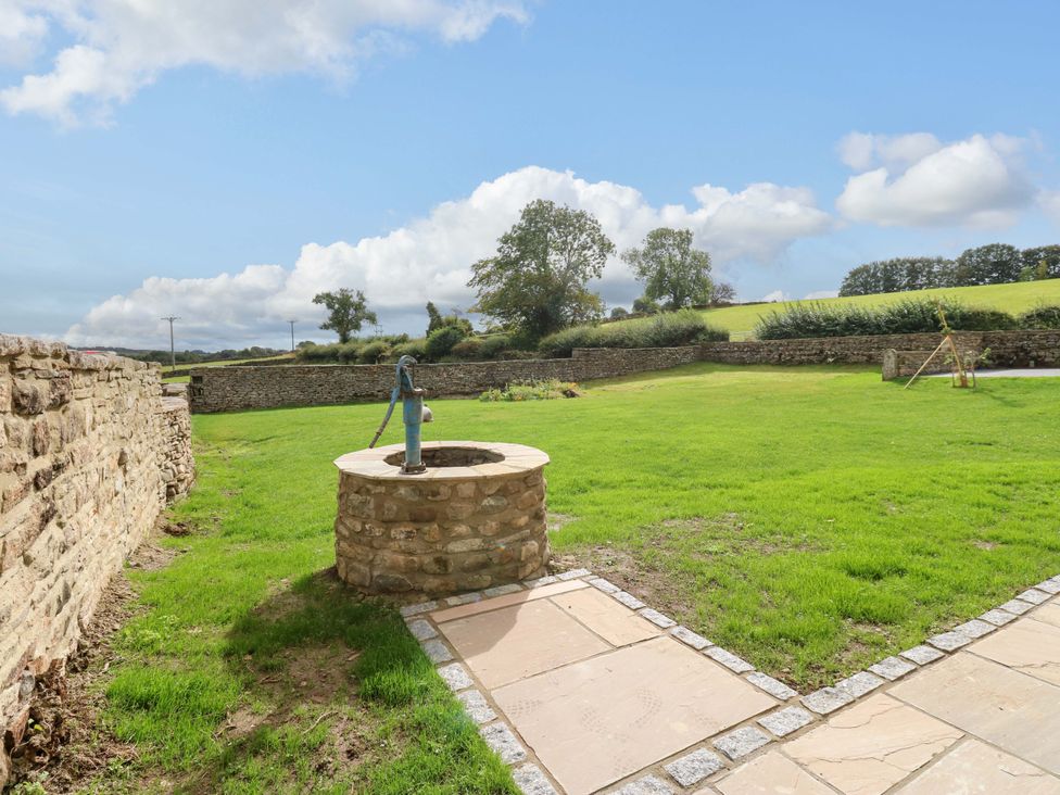 A garden with a well and grassy area at Eastfield Farm in Barnard Castle