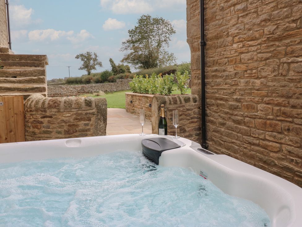 A hot tub with a champagne bottle and glass at Eastfield Farm Mickleton, Teesdale
