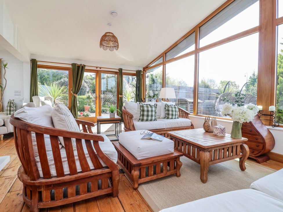 A sunroom with wooden furniture and large windows at Burlodge Swimbridge near Barnstaple