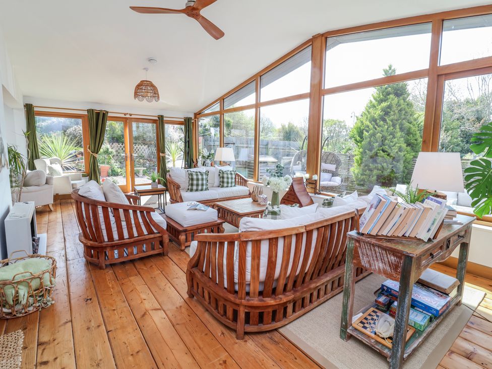 A conservatory with wooden furniture and windows at Burlodge Swimbridge near Barnstaple