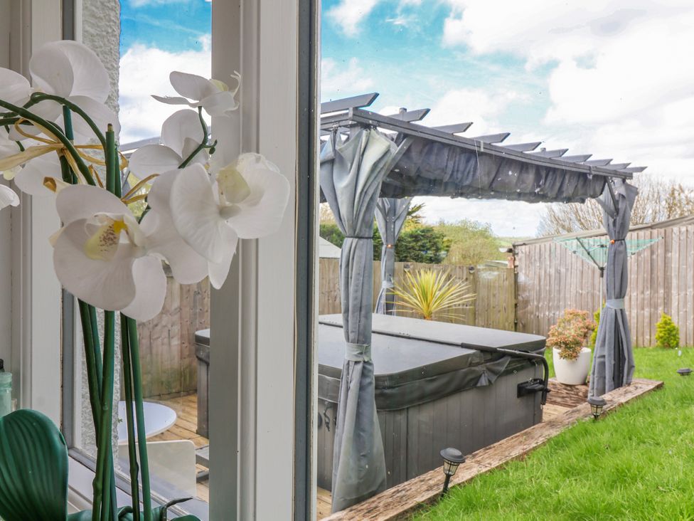 A garden with a hot tub and pergola viewed from indoors at Burlodge Swimbridge near Barnstaple