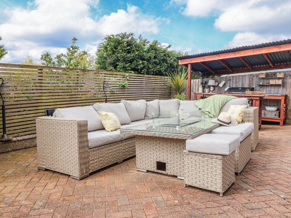 An outdoor patio with a sofa and glass table at Burlodge in Swimbridge near Barnstaple