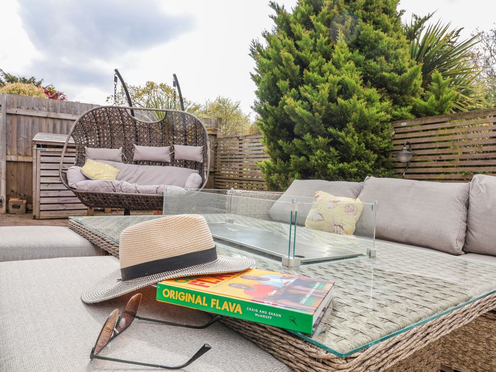 An outdoor seating area with a sofa and hanging chair at Burlodge in Swimbridge near Barnstaple