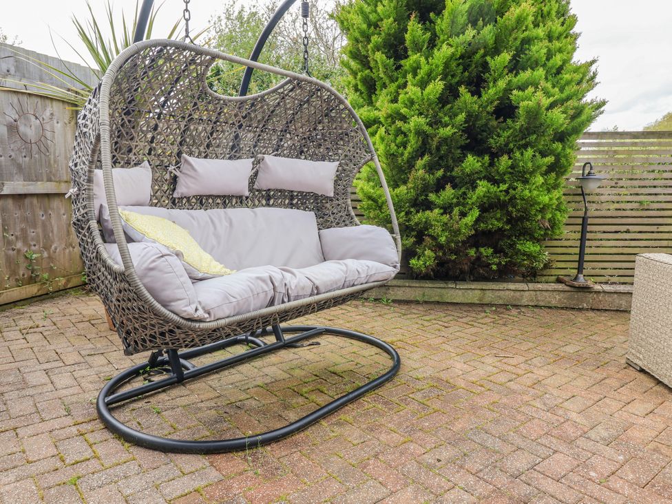 A hanging chair on a patio area at Burlodge Swimbridge near Barnstaple