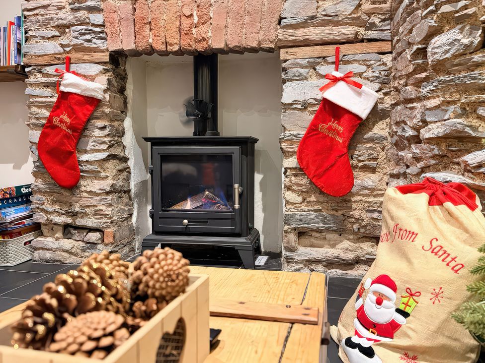 A living room with a fireplace and Christmas decorations at The Nook in Brixham