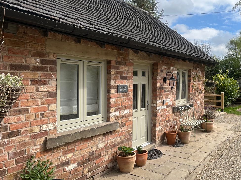 An outdoor view of a brick cottage with a sign at Bay Tree Cottage in Turnditch near Belper