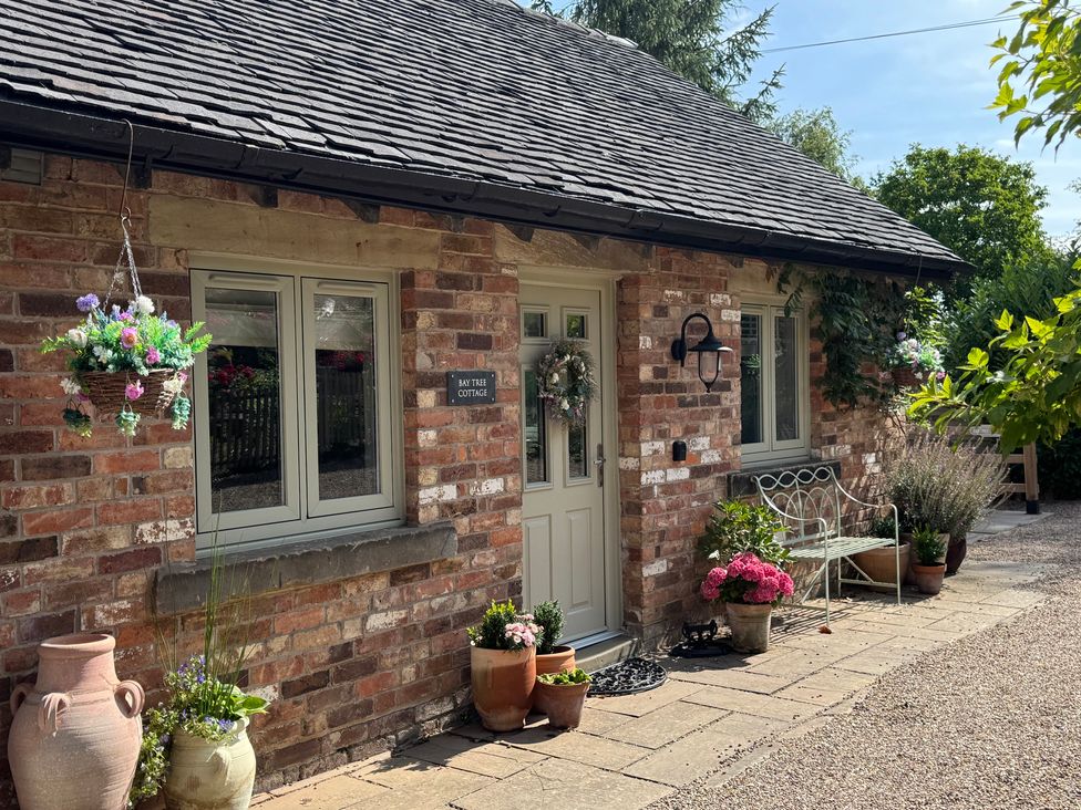 A cottage entrance with flowers and a bench at Bay Tree Cottage in Turnditch near Belper