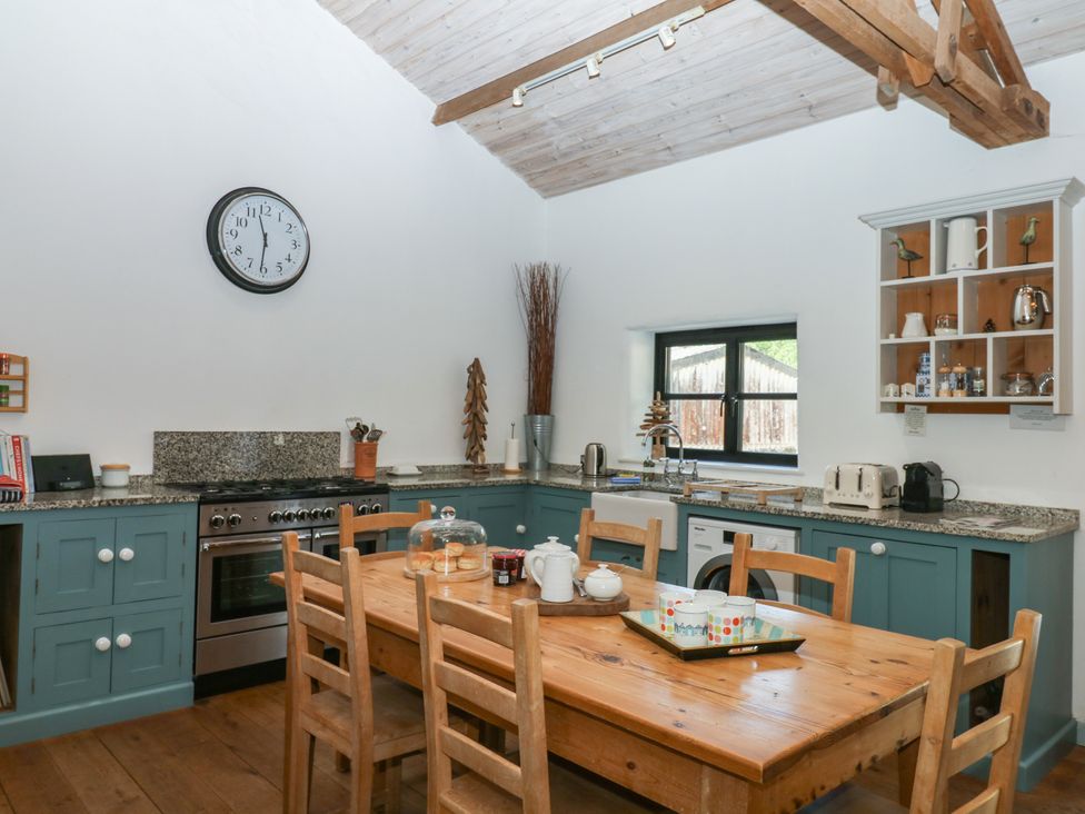 A kitchen with a dining table and stove at Burrows in Venn Ottery near Sidmouth