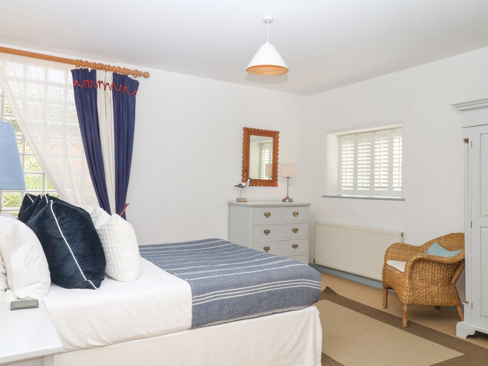A bedroom with a bed and dresser at Burrows in Venn Ottery near Sidmouth