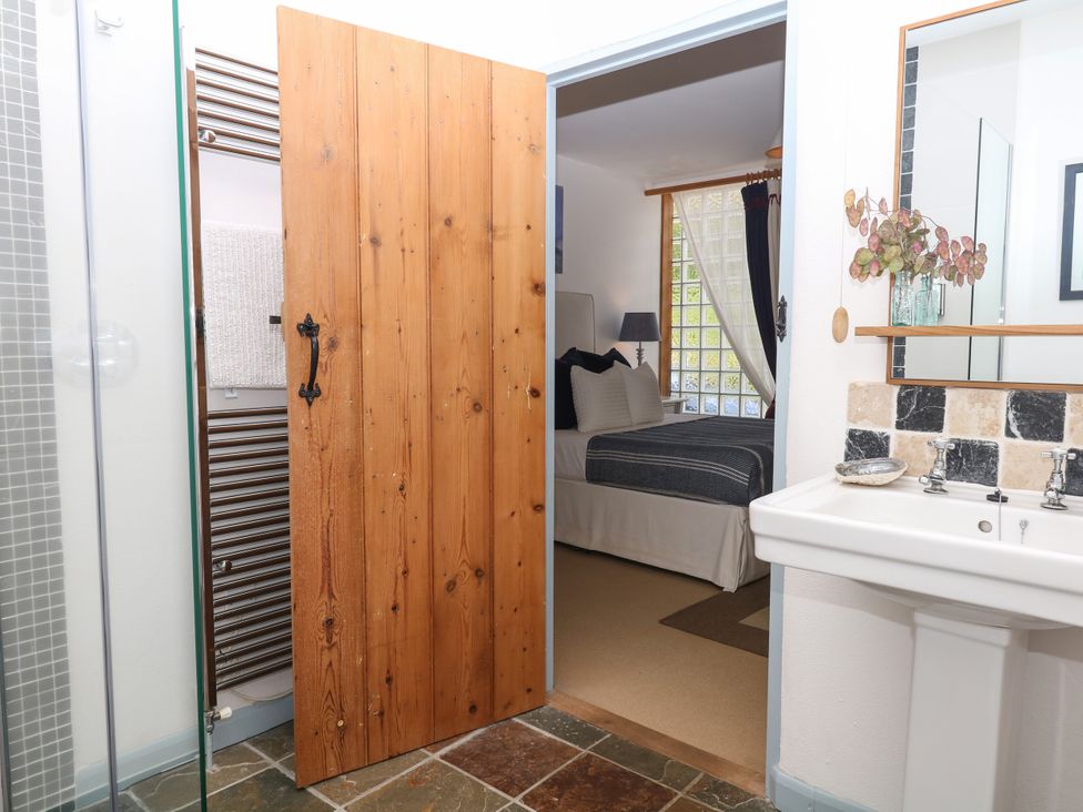 A bathroom with a sink and towel radiator leading to a bedroom at Burrows in Venn Ottery near Sidmouth