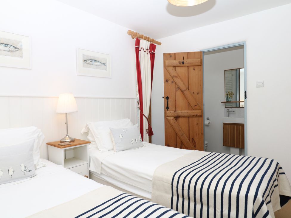 A bedroom with two beds and a wooden door at Burrows in Venn Ottery near Sidmouth