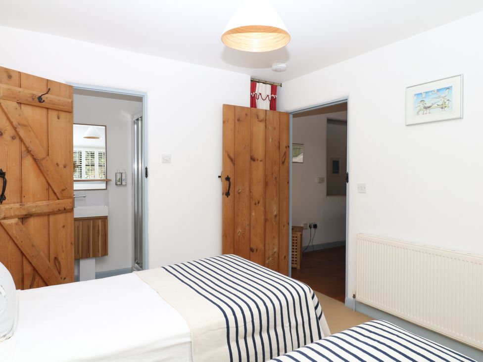 A bedroom with two beds and doors leading to another room at Burrows Venn Ottery near Sidmouth