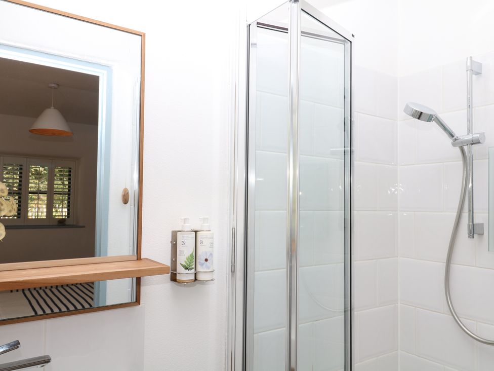 A bathroom with a shower and mirror at Burrows in Venn Ottery near Sidmouth